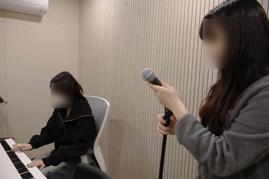 보컬 학원에서 보컬 트레이닝 수업을 듣고 있는 수강생 모습
